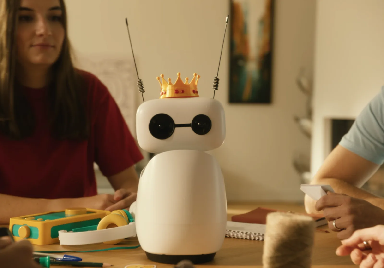 Reachy Mini wearing the crown at a table