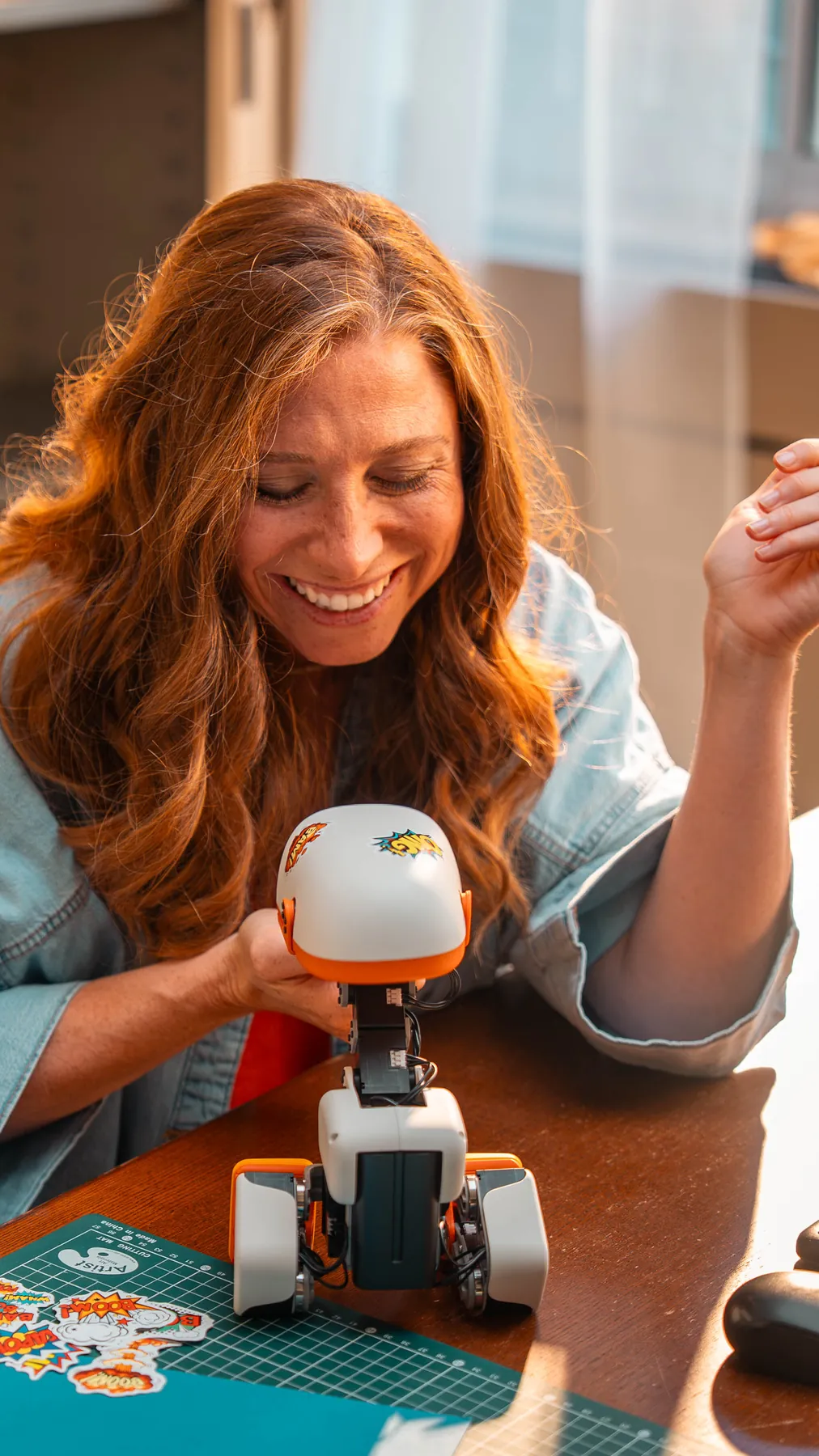 A woman laughing while playing with a Microduck at a table