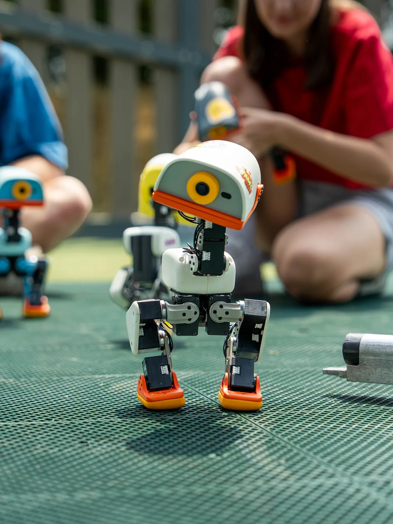 A Microduck walking across a green games table surrounded by people